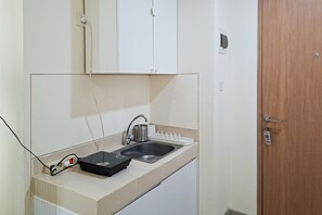 Eine kleine Küchenzeile mit Spüle, Steckschienen und Schrank.