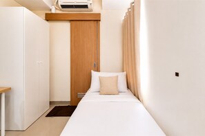 A small, neatly arranged bedroom with a bed, a wardrobe, a desk, and an air conditioning unit. - Splendid Studio At Apartment B Residence (Tangerang)