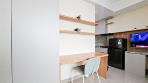A modern kitchen with a wooden countertop, a grey chair, a black refrigerator, and a TV mounted on the wall. - Comfortable And Homey Studio Room At Apartment B Residence (Tangerang)