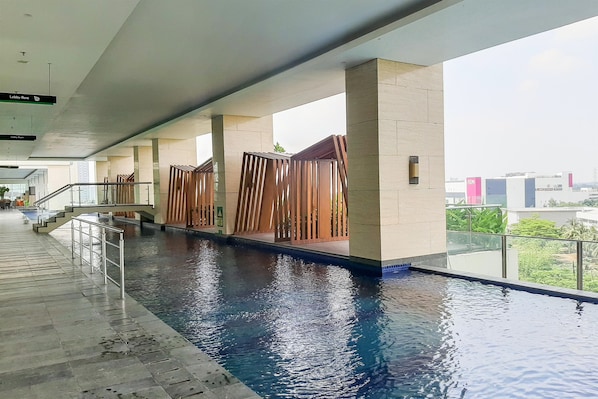 Piscina interior moderna com água cristalina, ladeada por um caminho de azulejos e barreiras de madeira.