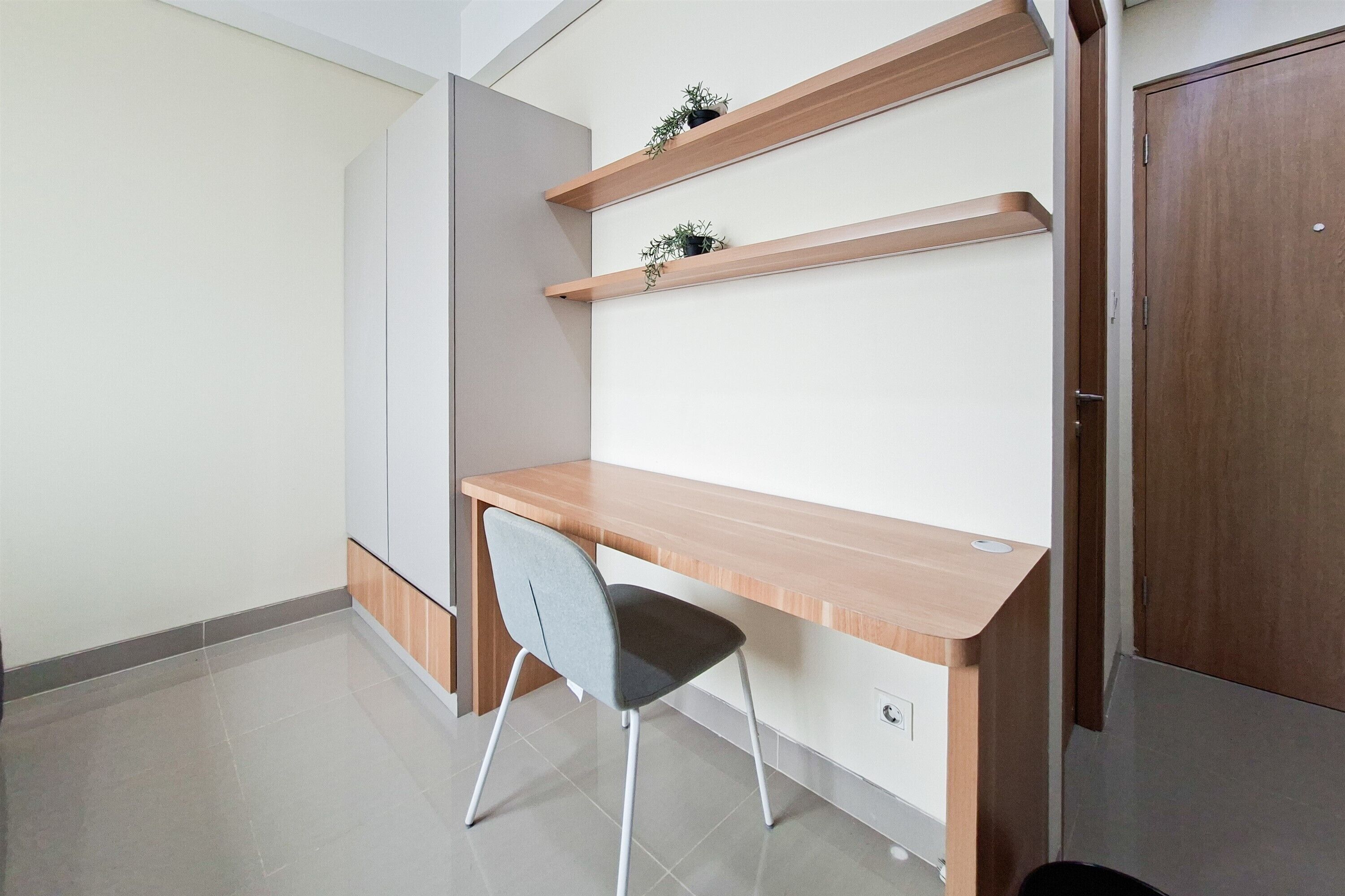 A room with a wooden desk, a grey chair, and a wardrobe.