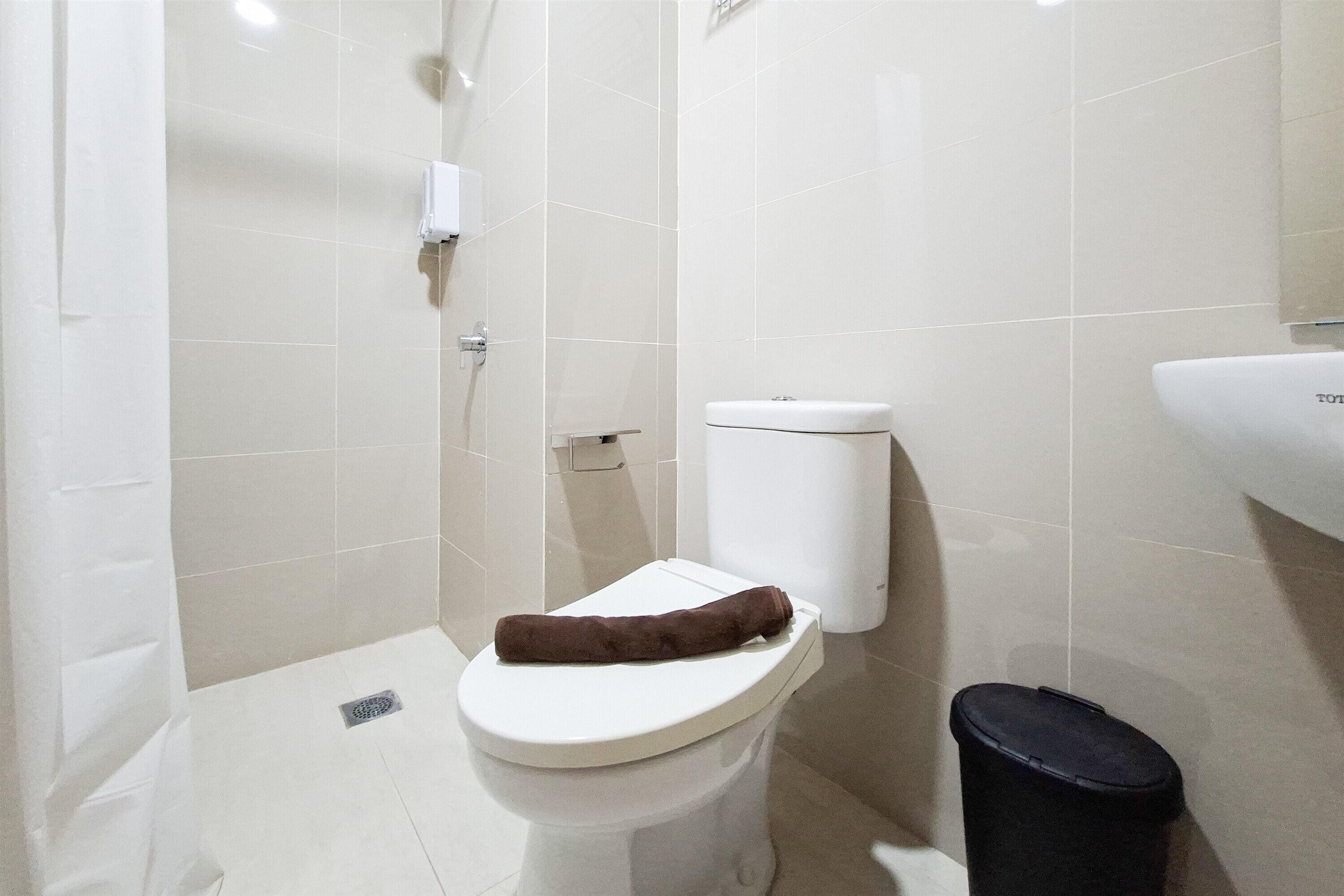 Un baño con inodoro, un basurero negro y zona de ducha.