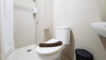 Un baño con inodoro, un basurero negro y zona de ducha.