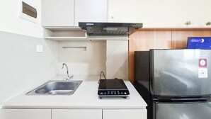 A compact kitchen with a built-in gas stove, a stainless steel sink, and a refrigerator. - Comfortable And Homey Studio Room At Apartment B Residence (Tangerang)