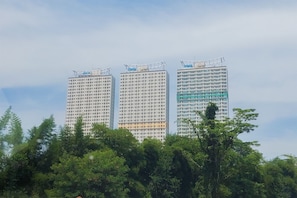 Três edifícios altos com uma grande quantidade de janelas e uma fachada verde à direita.