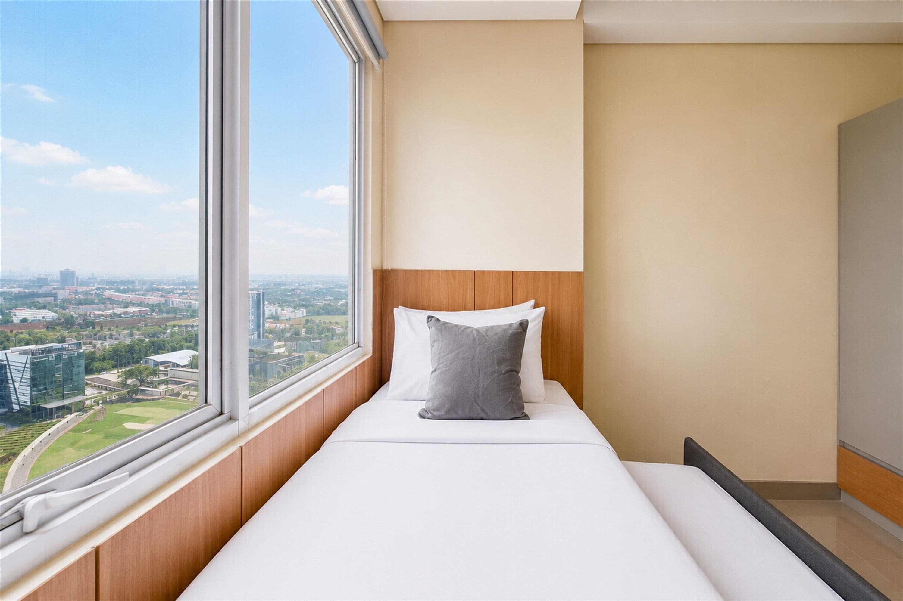 Una habitación de hotel con cama, ventana y vista a la ciudad, además de un cabecero de madera.
