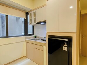 A compact kitchen with a built-in refrigerator, a sink, and cabinets.