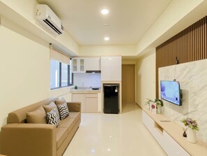 Moderni huoneisto, jossa on olohuone, pieni keittiö ja televisio, joka on asennettu marmoriseinälle.