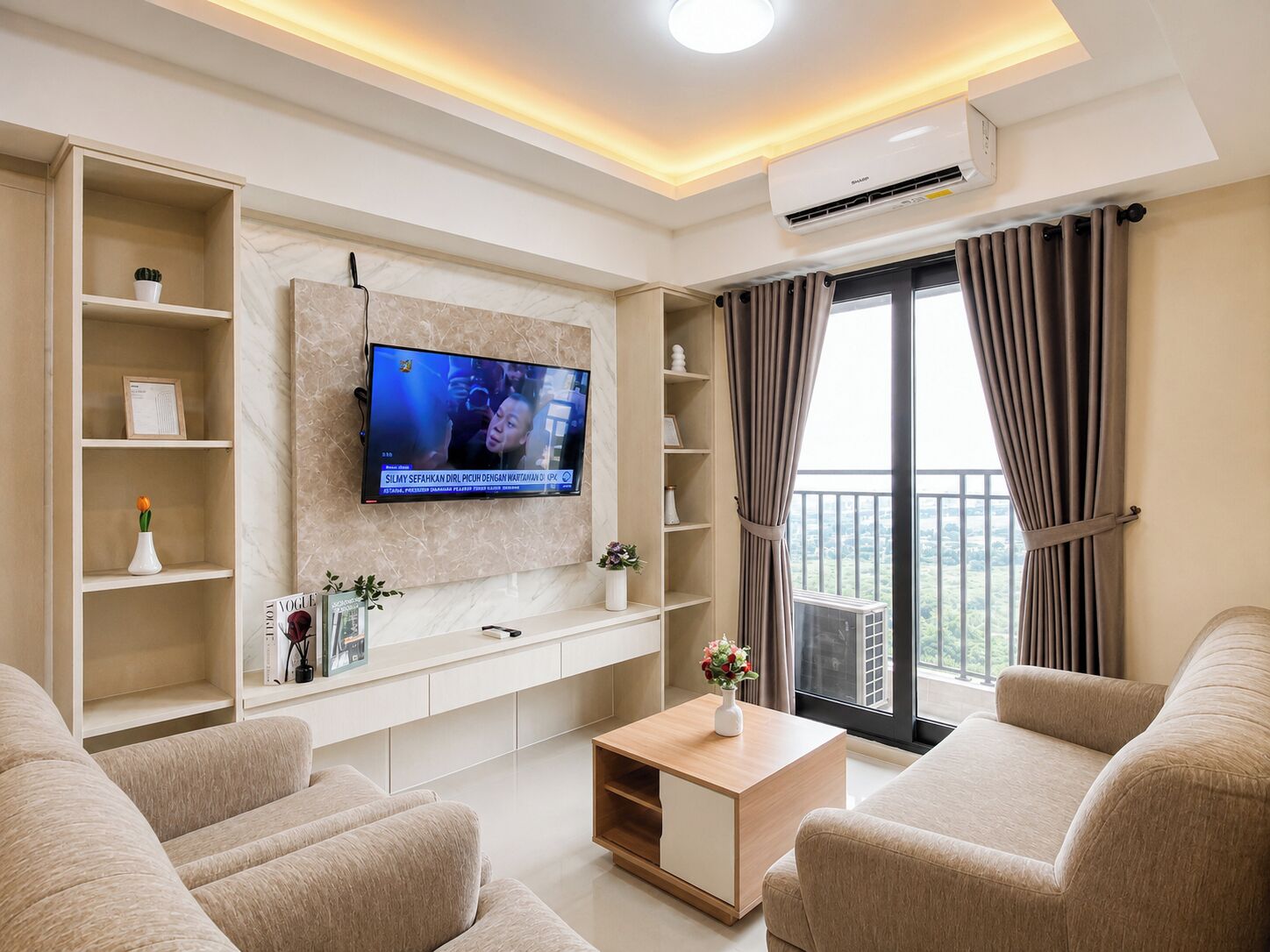 A modern living room with a flat-screen TV mounted on the wall, a sofa set, a coffee table, and a balcony with curtains.