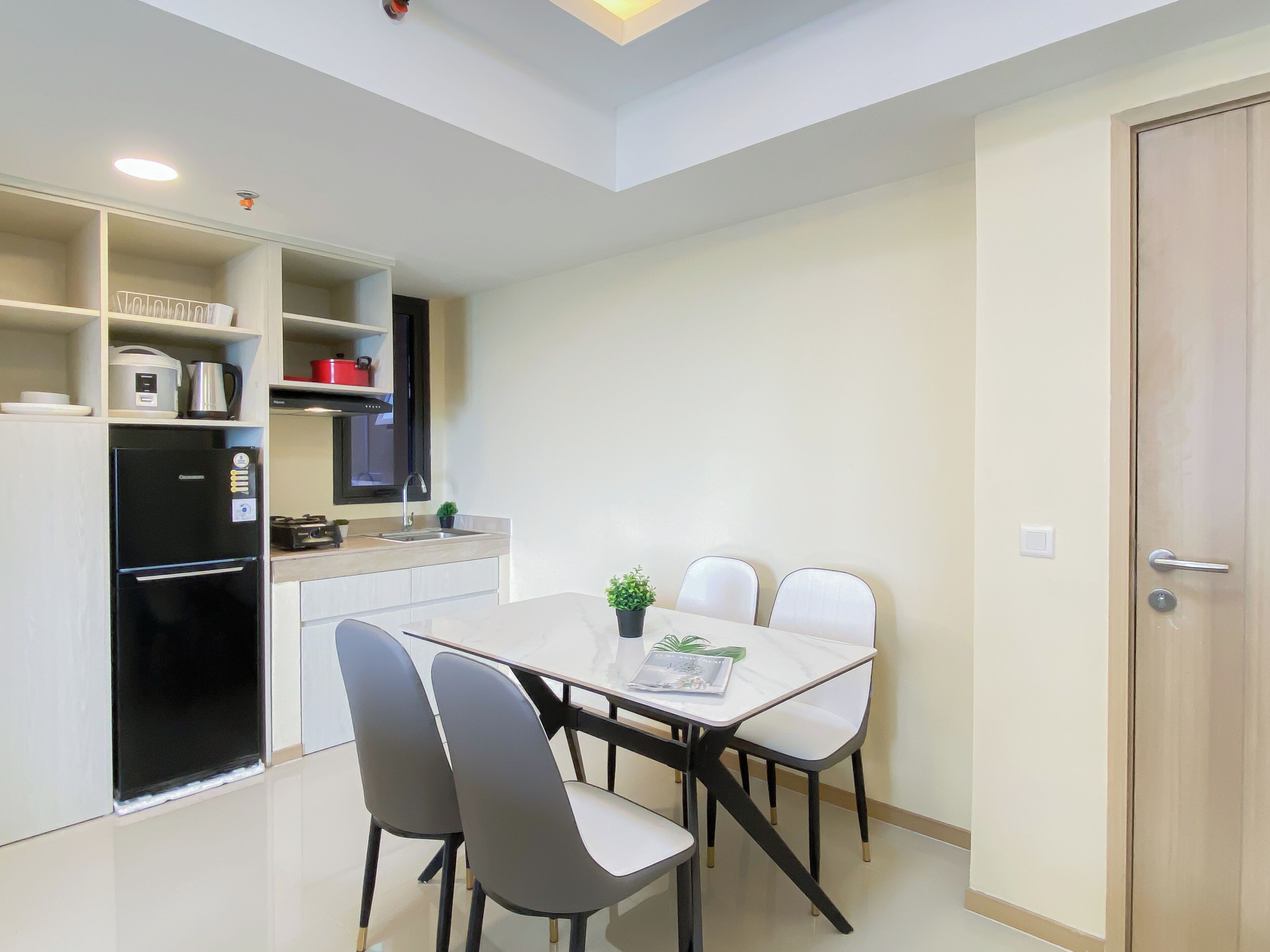 Cocina compacta con electrodomésticos modernos, una mesa de comedor con sillas y una puerta a la derecha.