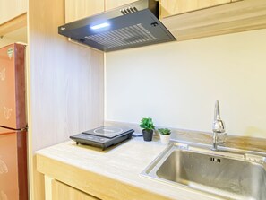 Cuina amb taula vitroceràmica, un rentapeus d'acer inoxidable i armaris de fusta.