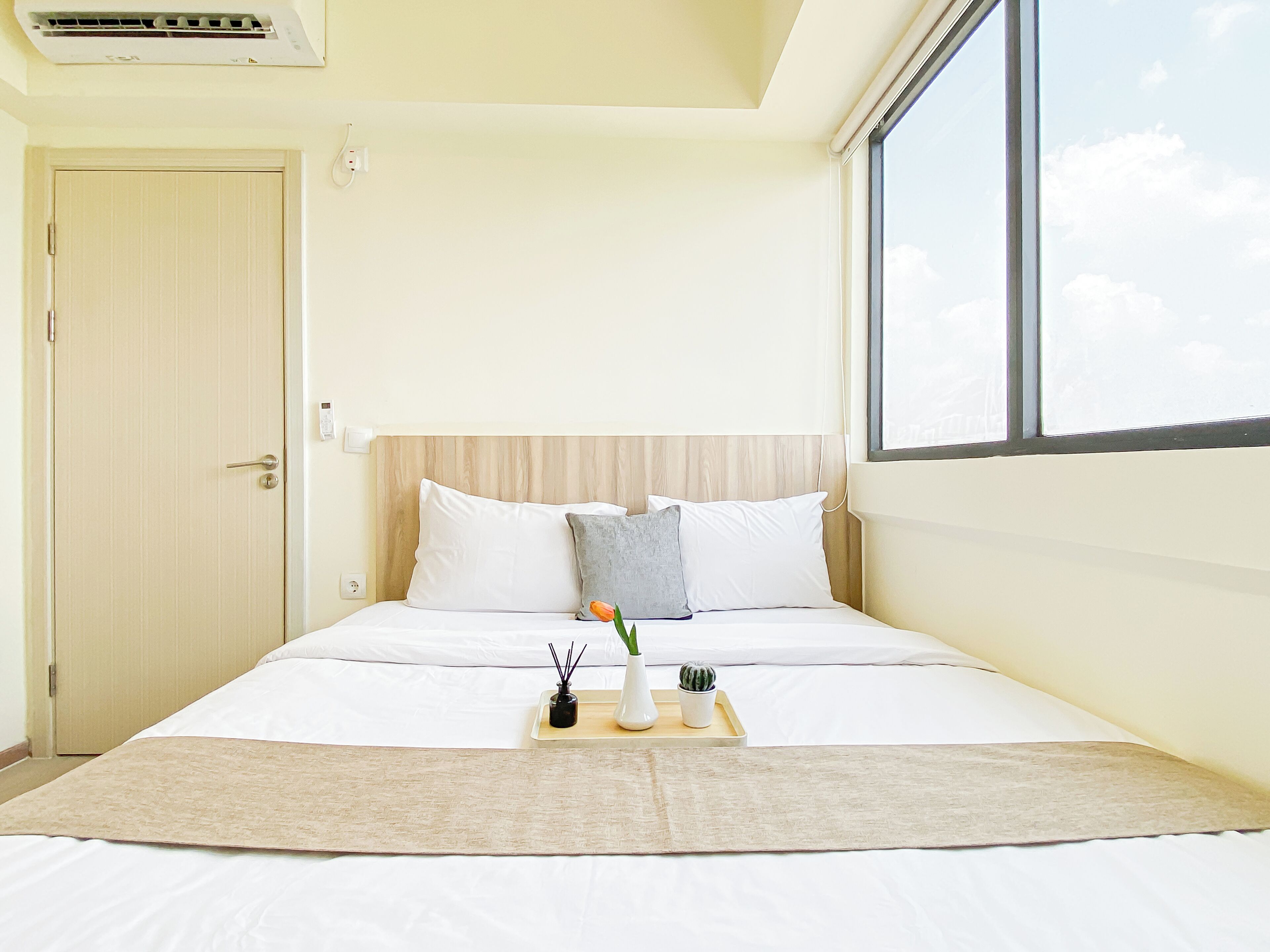 A hotel room with a bed, a window, and a door.