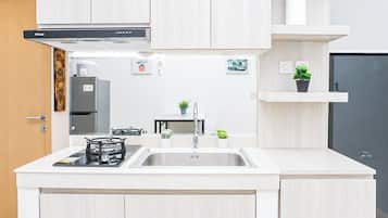 A modern kitchen with a gas stove, stainless steel sink, and light wood cabinetry.