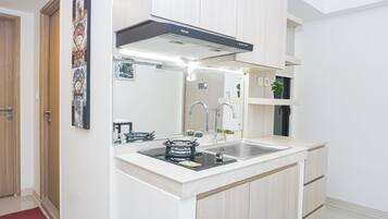 Una cocina compacta con estufa a gas integrada, pileta de acero inoxidable y campana extractora moderna.