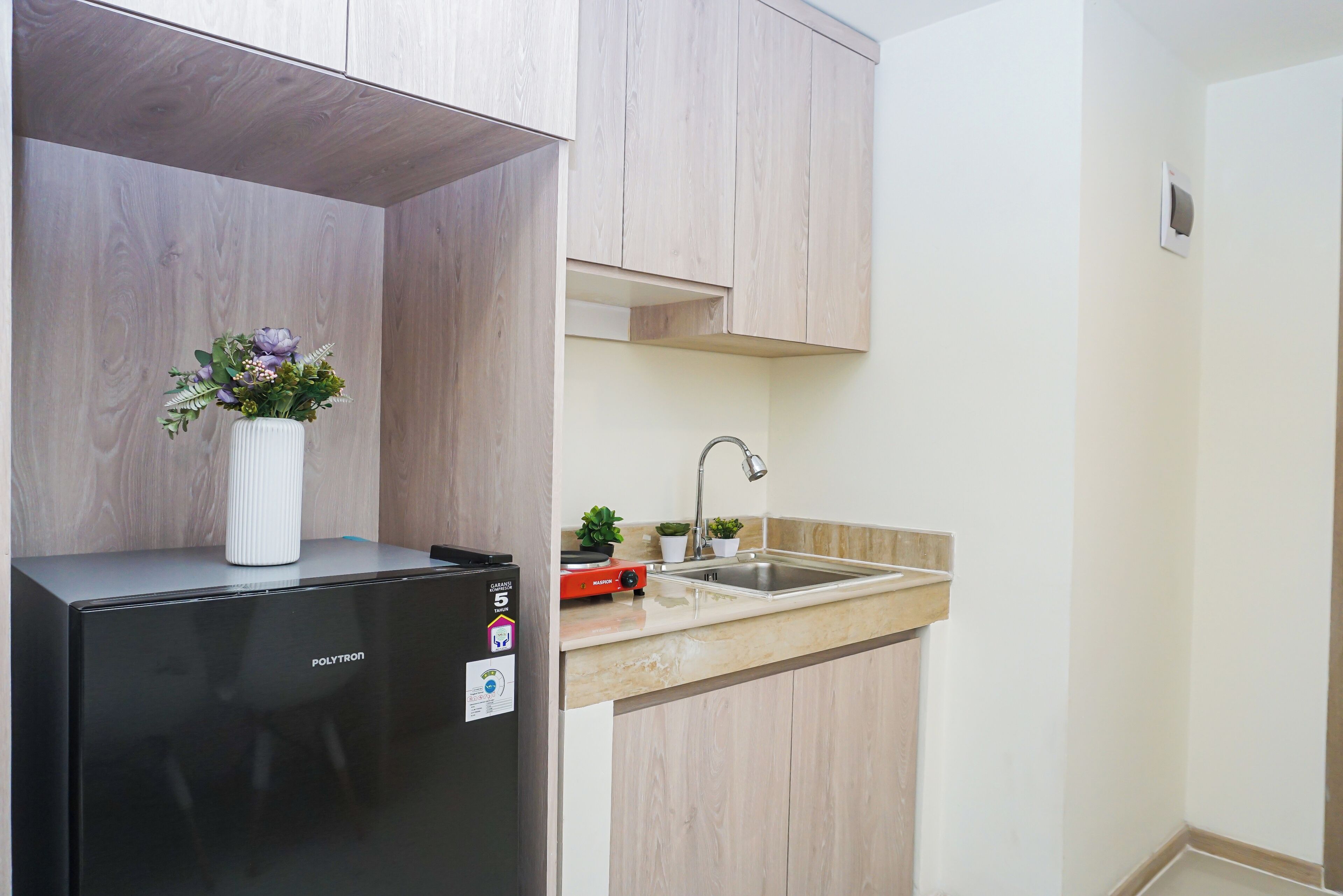 Una cocina compacta con un refrigerador negro, un lavamanos y armarios de madera.