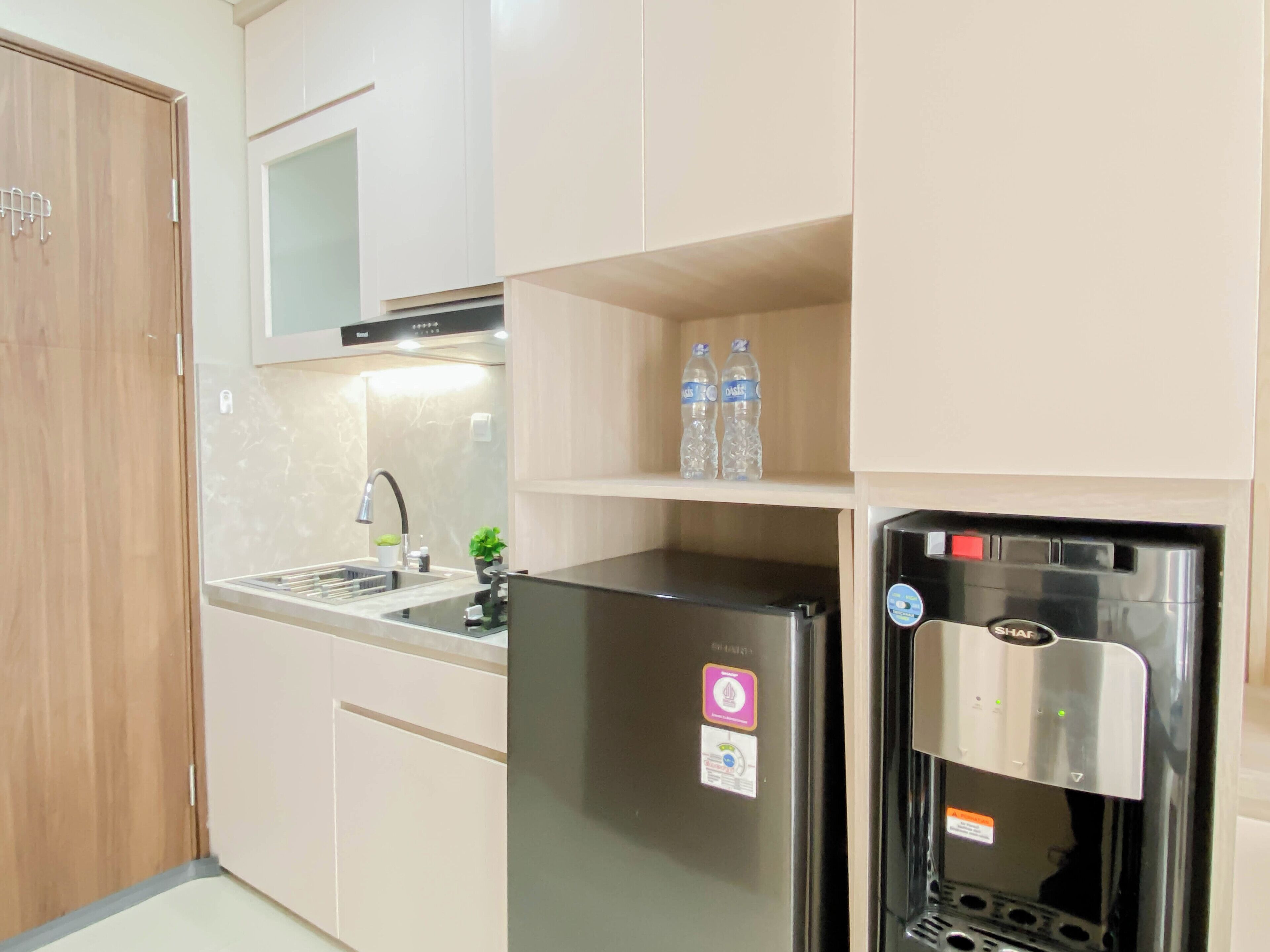Una cocina con refrigerador empotrado, dispensador de agua y pileta.