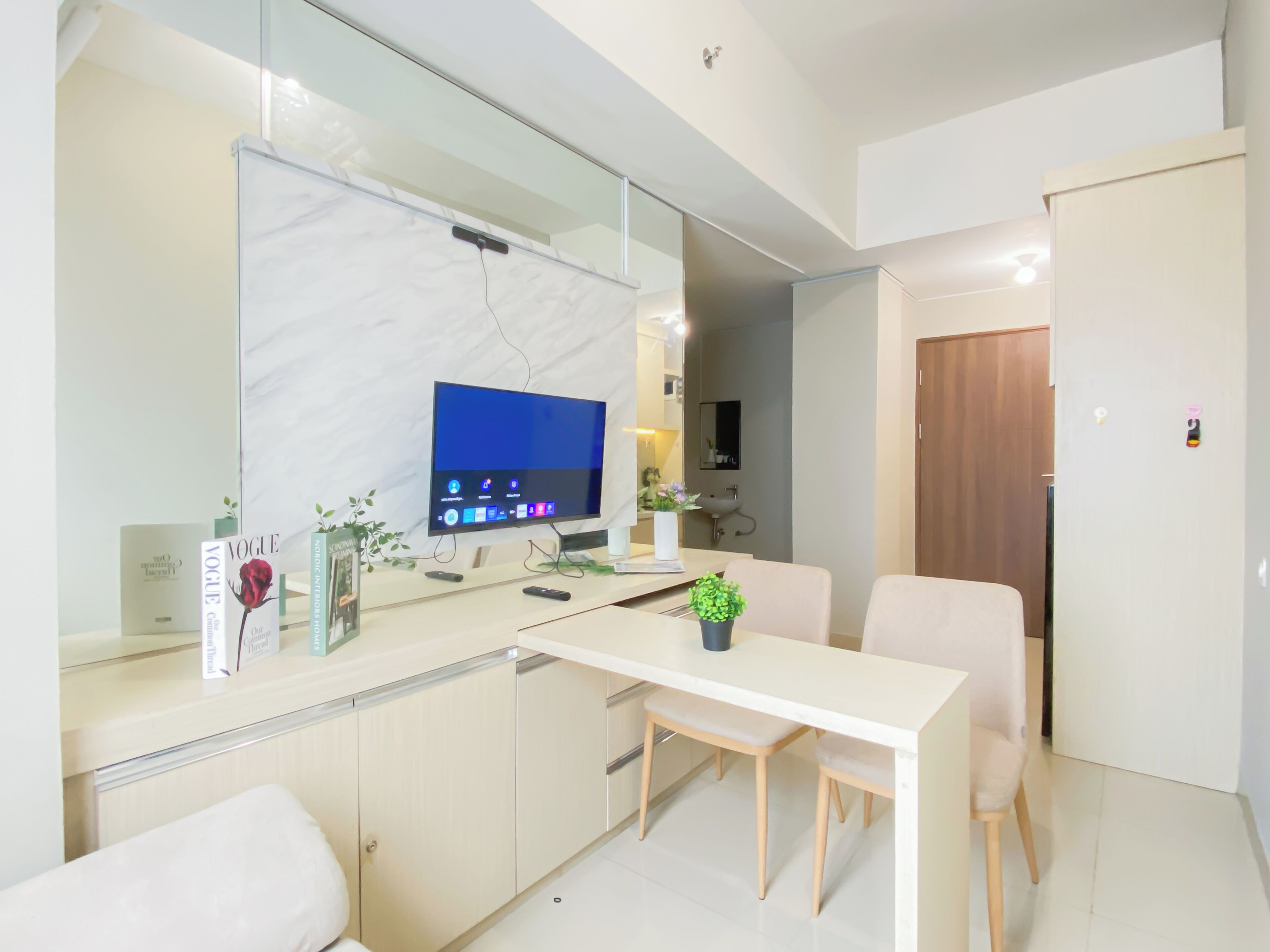 Una cocina moderna con encimera de mármol, televisor integrado y comedor con mesa y sillas.