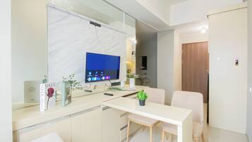 Una cocina moderna con encimera de mármol, televisor integrado y comedor con mesa y sillas.