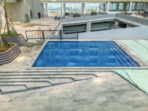 Ein Dachpool mit Stufen, die zu einer unteren Ebene führen, umgeben von einem modernen Gebäude mit großen Fenstern.