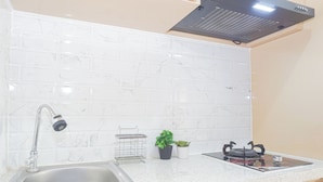 Una cocina con un lavamanos de acero inoxidable, una estufa a gas, un extractor de humos y un salpicadero de mármol.