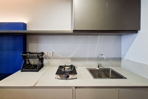 Una cocina con estufa a gas, lavamanos y alacenas.