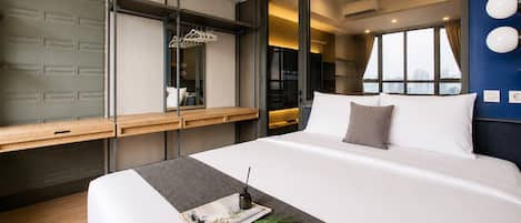 Una habitación de hotel moderna con una cama grande, un escritorio de madera, un espejo y vistas de la ciudad.