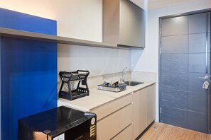A compact kitchenette with a gas stove, a coffee maker, and a sink. - Chic With Urban Design 1Br Apartment At Collins Boulevard (Tangerang)