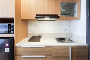 Une cuisine moderne avec des meubles en bois, un four encastré, un évier en acier inoxydable et un plan de travail doté d’une balance numérique.