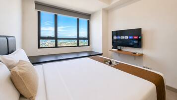 A hotel room with a large bed, a television mounted on the wall, and a window with a city view.