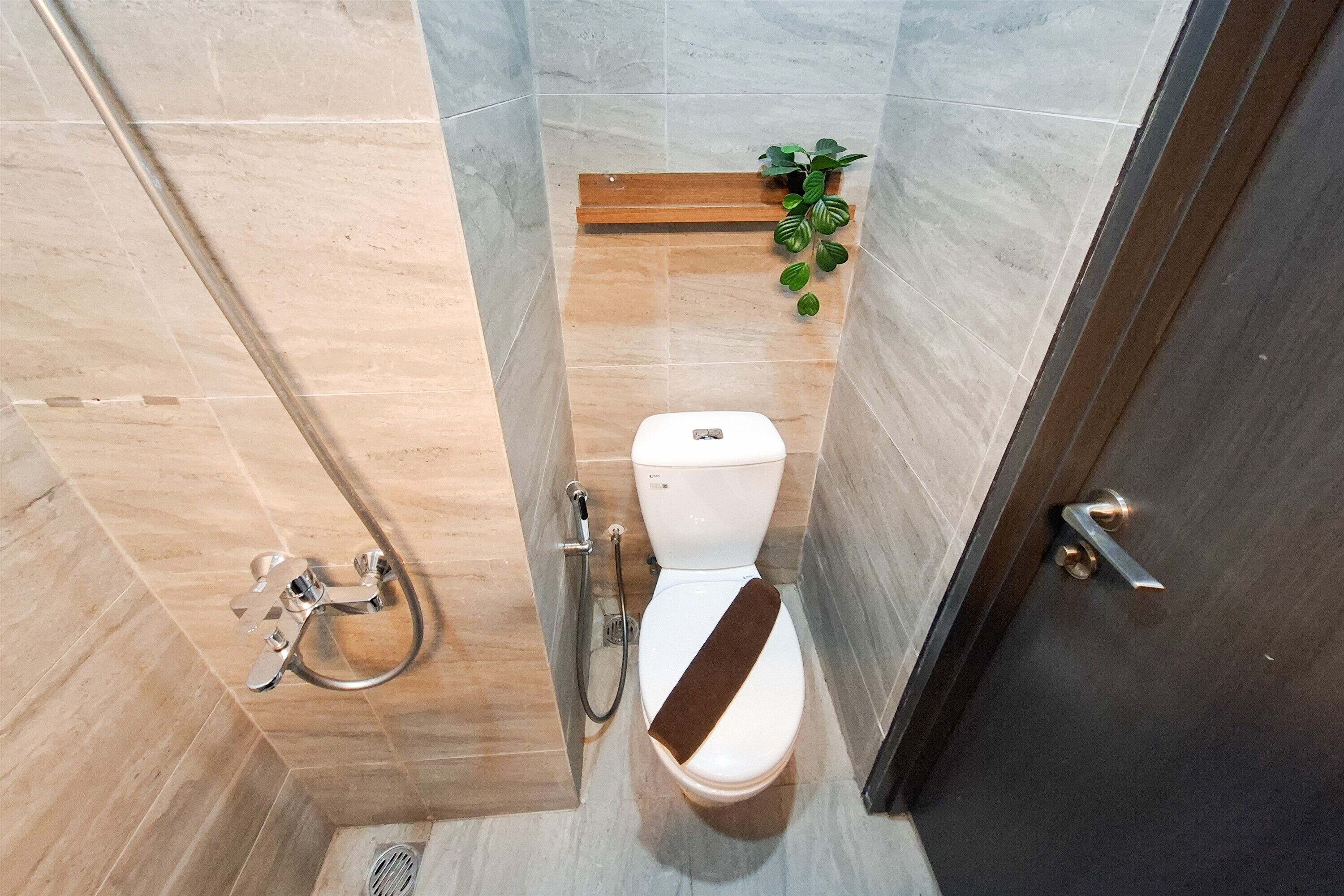 Ein Badezimmer mit Dusche, Toilette und einer kleinen Pflanze.