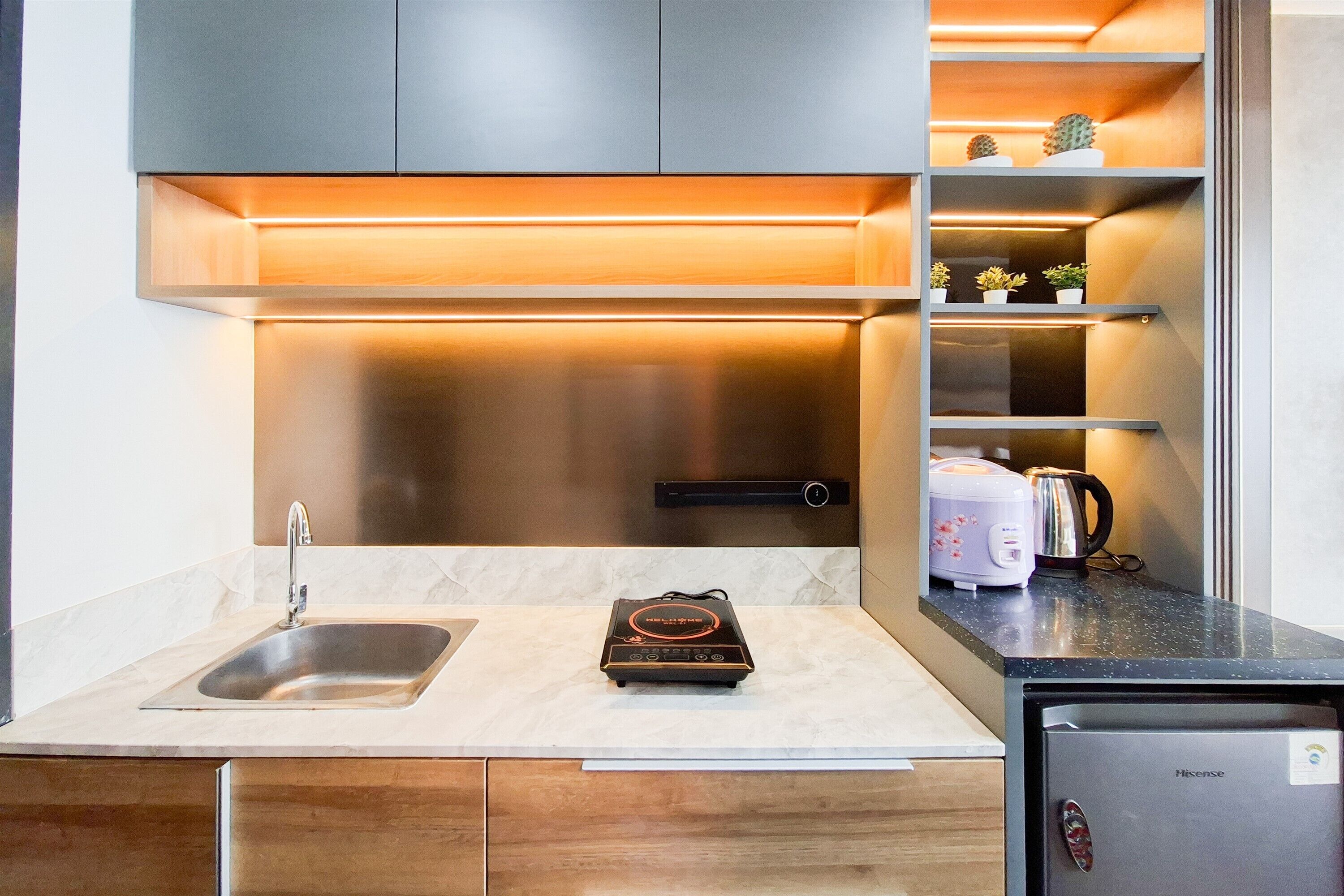 Una cocina moderna con un lavamanos de acero inoxidable, un refrigerador compacto y un horno empotrado.