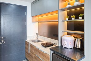 Eine moderne Küche mit Backofen, Spüle und Arbeitsplatte, auf der ein Reiskocher und ein Wasserkocher stehen.