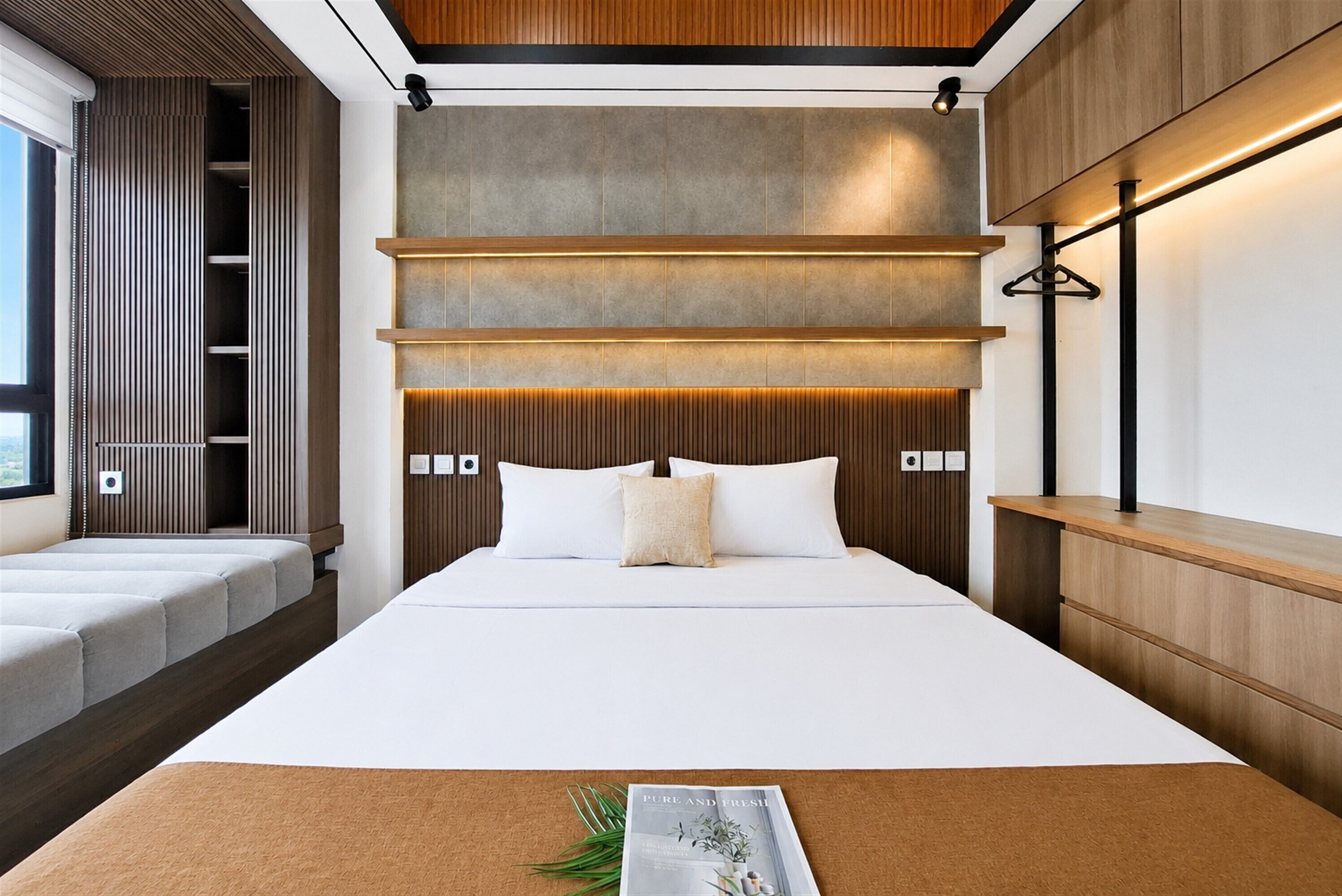 A modern bedroom with a large bed, wooden headboard, and built-in lighting.