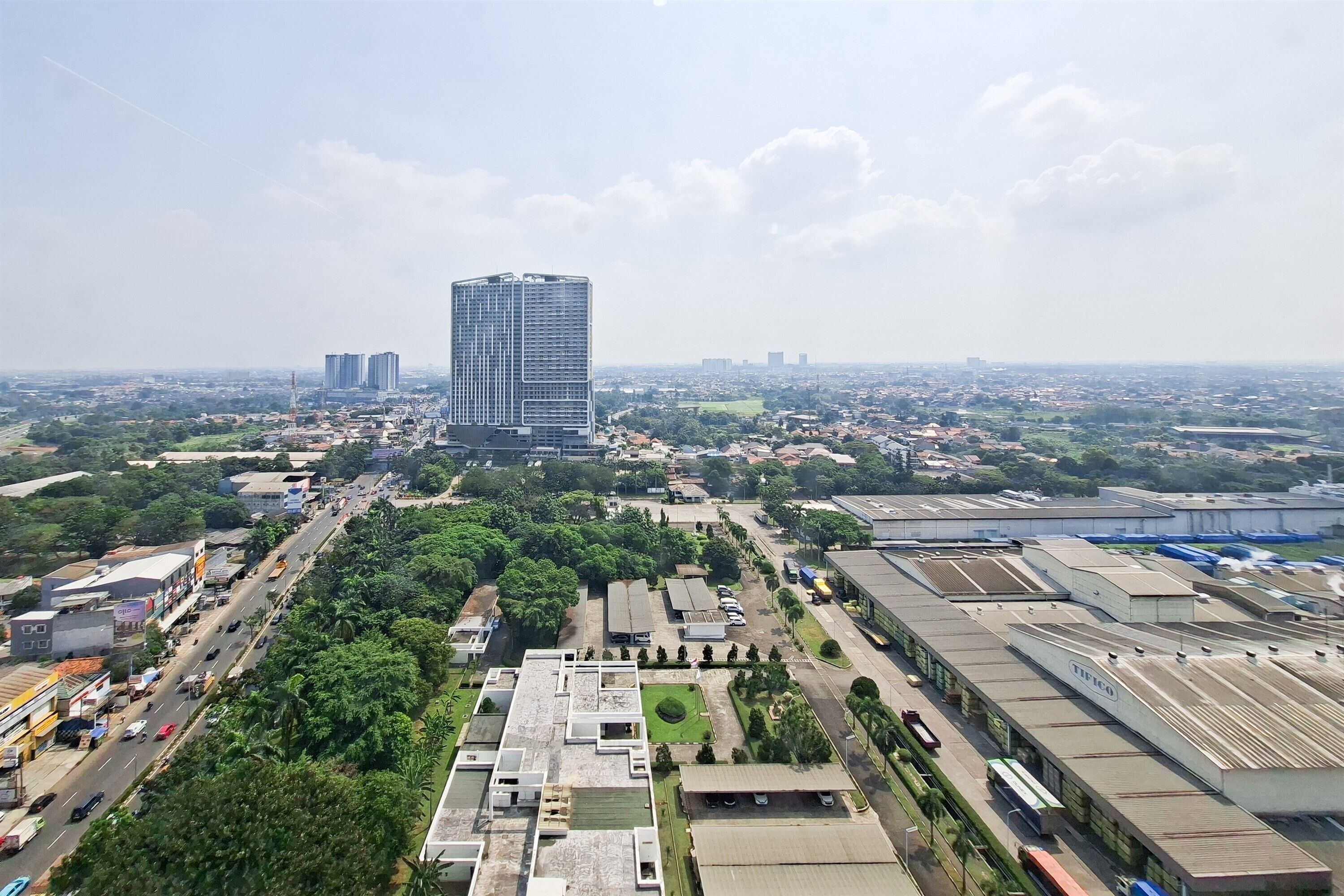 A high-rise building with a modern design, surrounded by a mix of commercial and residential areas, with visible roads and greenery.