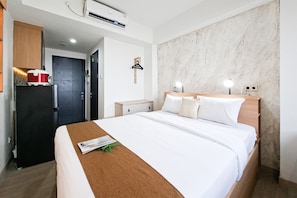 Une chambre d’hôtel comprenant un lit, une table de chevet, un radiateur fixé au mur, une porte et un mur dont la texture ressemble à du marbre.