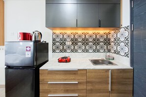 A compact kitchen with a refrigerator, a coffee maker, a toaster, and a sink. - Great Deal Studio At Apartment Collins Boulevard (Tangerang)