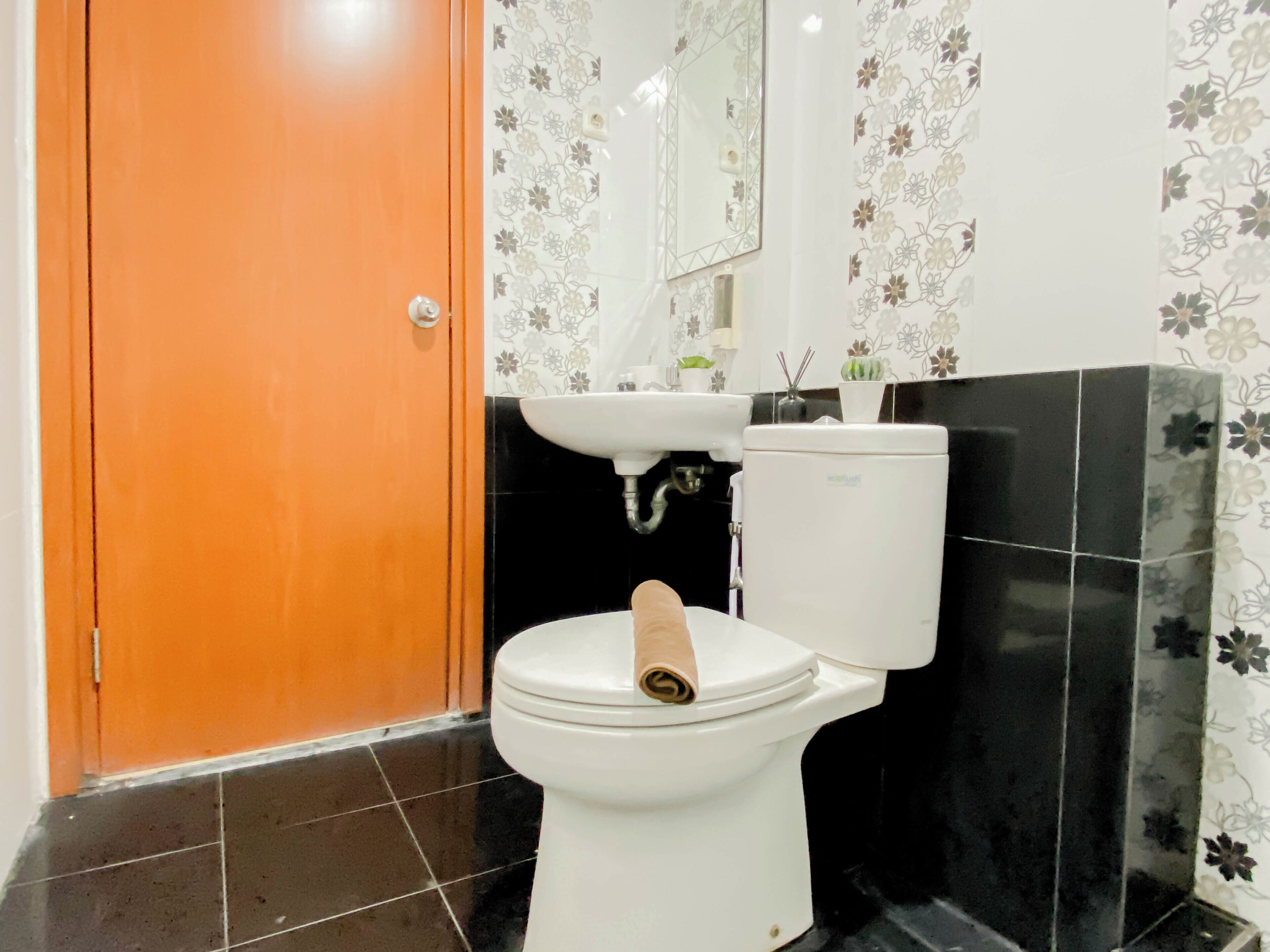 A bathroom with a toilet, sink, and mirror.