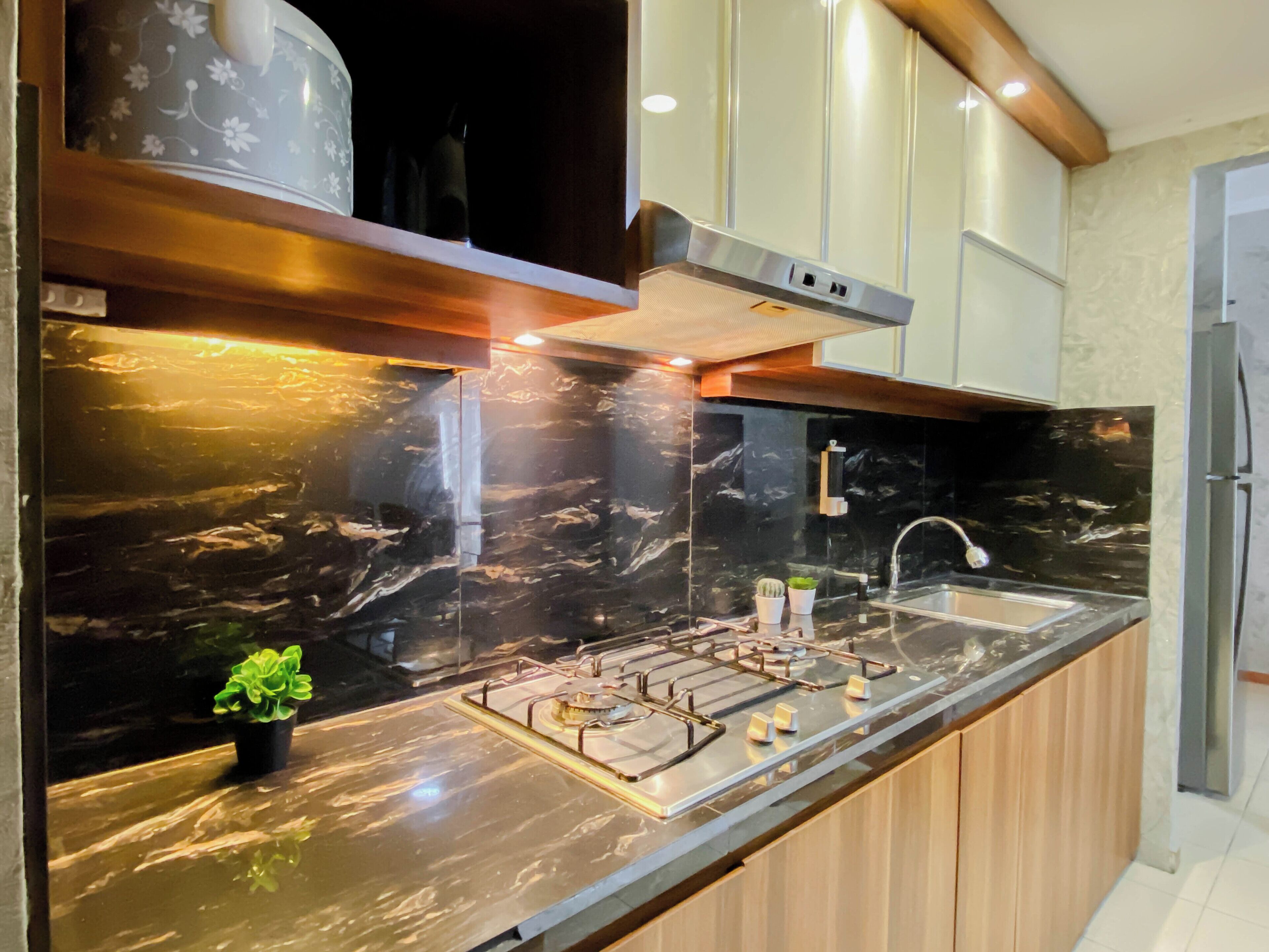A modern kitchen with a marble countertop, stainless steel appliances, and wooden cabinets.