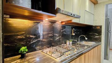 A modern kitchen with a marble countertop, stainless steel appliances, and wooden cabinets.