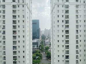 A high-rise residential building with multiple balconies, a central courtyard, and a view of surrounding high-rise buildings. - Classic And Strategic 3Br At Apartment Grand Palace Kemayoran (Jakarta)