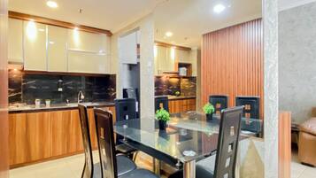 A modern kitchen with wooden cabinets, a marble countertop, and a glass dining table with chairs.