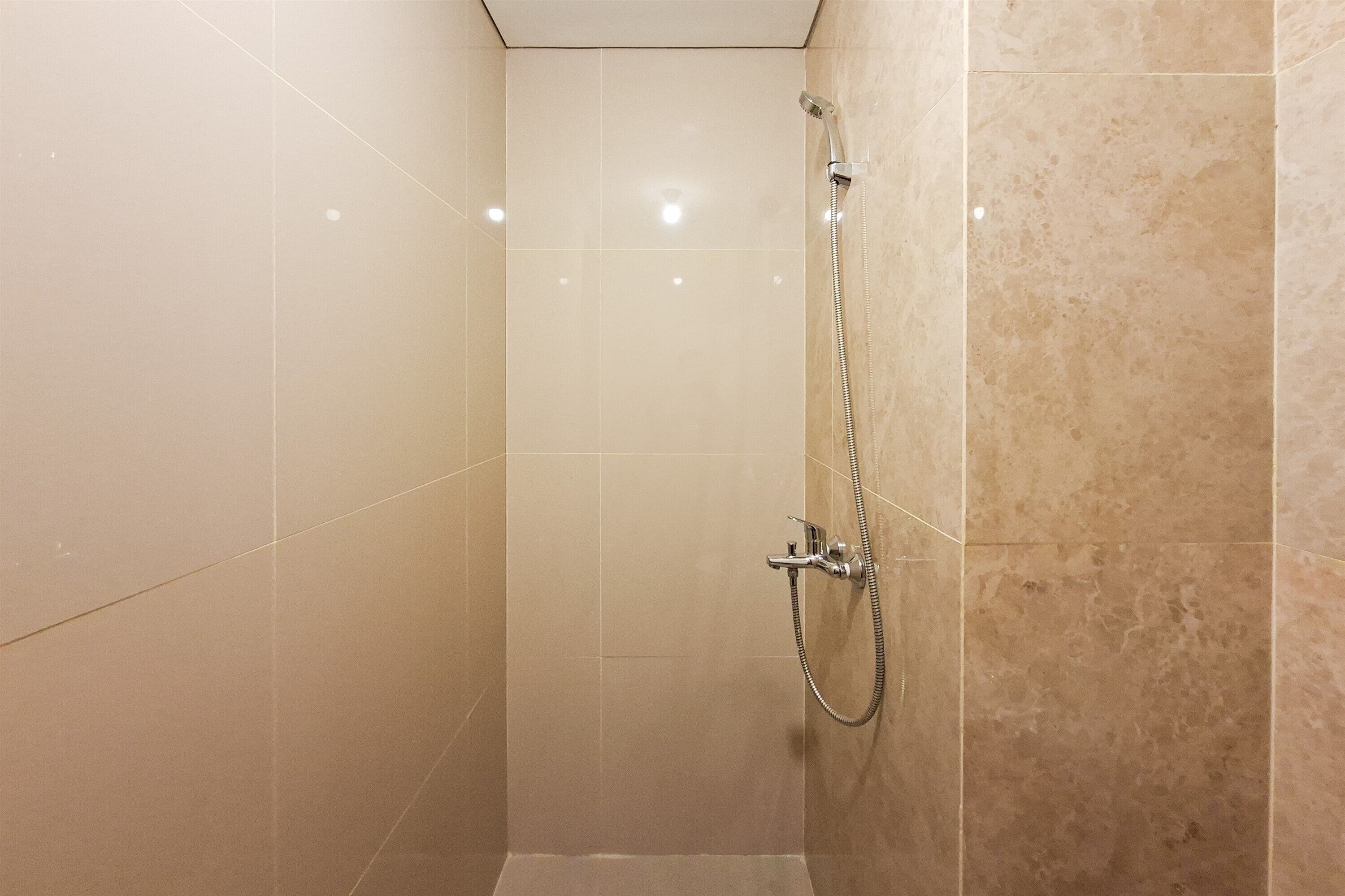 A small, enclosed shower area with a handheld showerhead and a fixed showerhead on the wall.