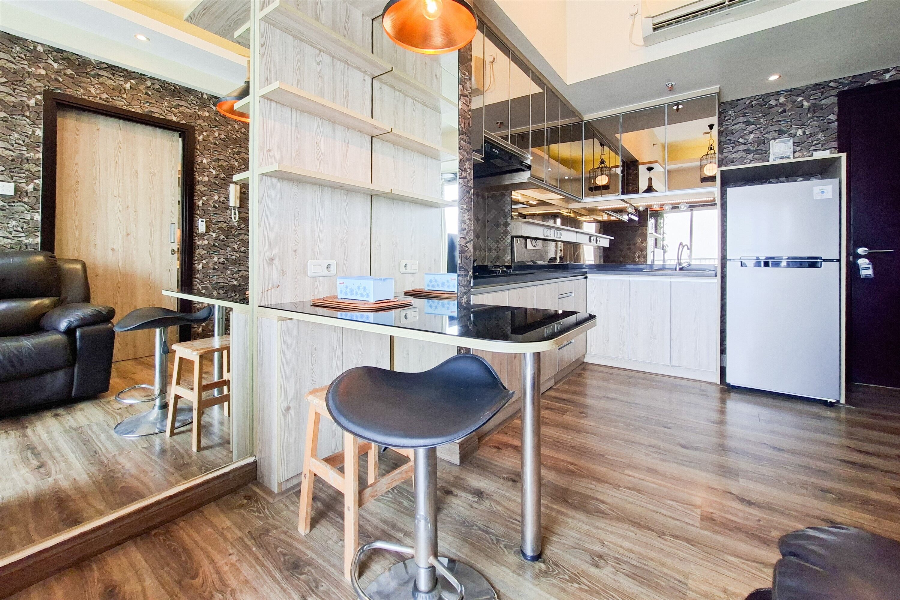 Een moderne keuken met een centraal eiland, een eethoek met een barkruk en een zwarte leren bank.