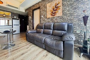 A modern living room with a leather sofa, a glass coffee table, and a stone wall.