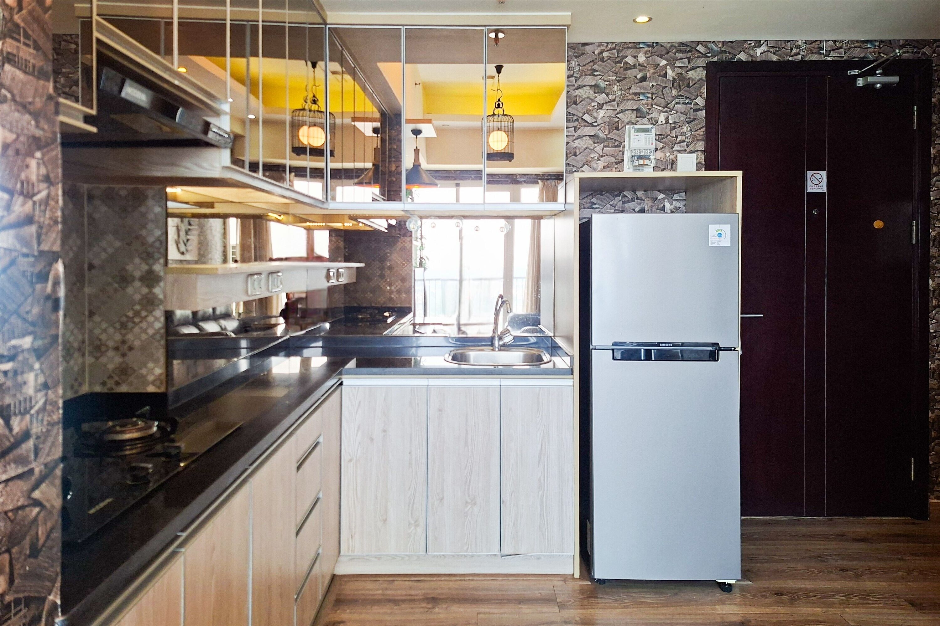A modern kitchen with a built-in stove, a refrigerator, and a stone accent wall.