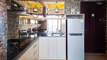 A modern kitchen with a built-in stove, a refrigerator, and a stone accent wall.