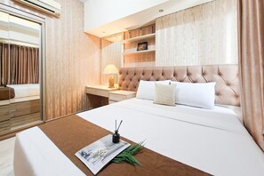 A hotel room with a large bed, a bedside table with a lamp, a mirror, and a wardrobe.
