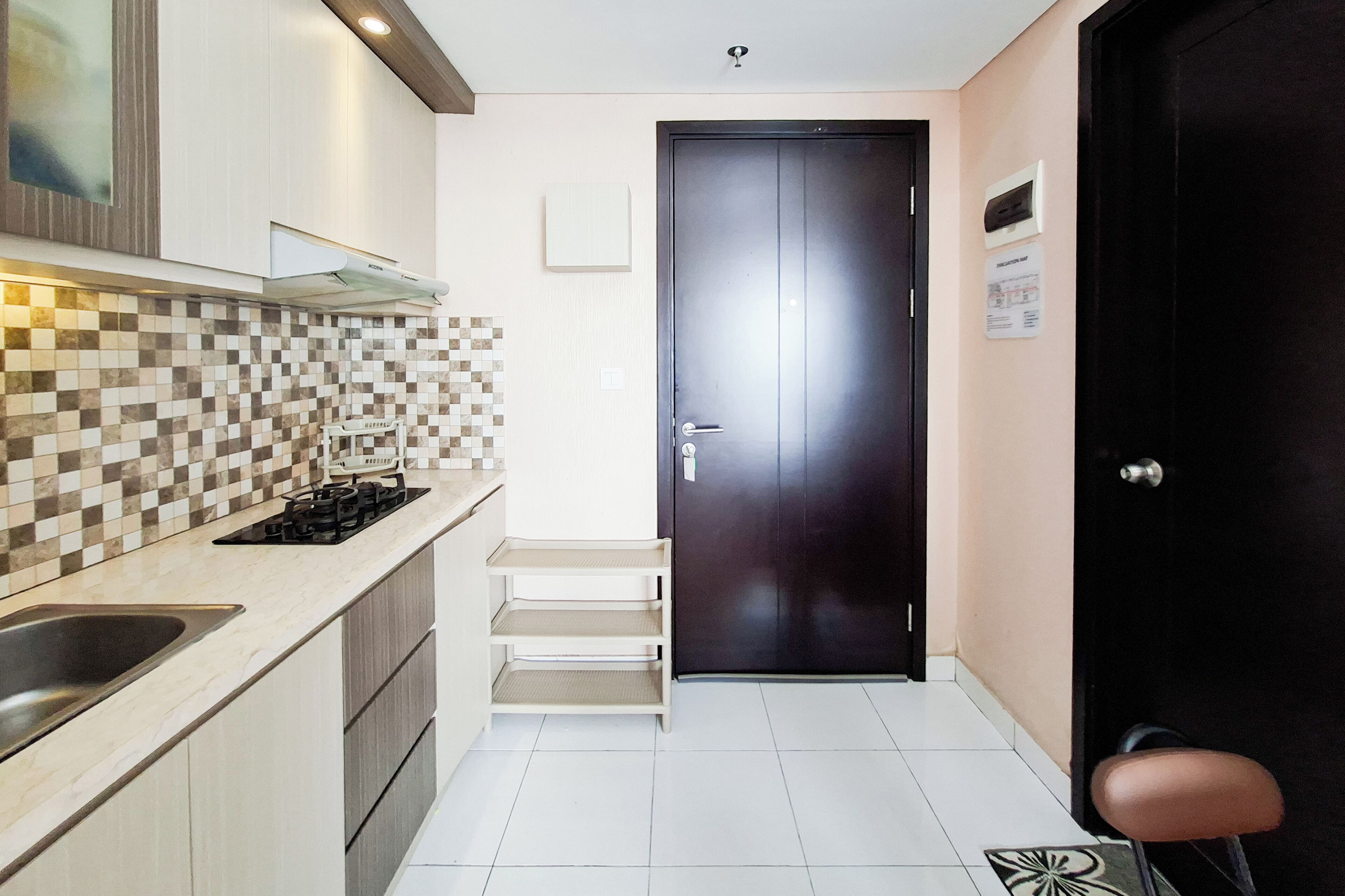 A modern kitchen with a tiled backsplash, a stove, a sink, and a dark door.