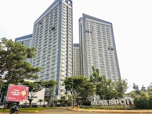 A high-rise building with multiple balconies and a sign indicating a show unit. - Airy Studio At Casa De Parco Apartment (Tangerang)