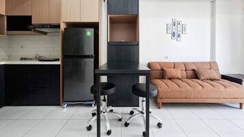 Una cocina moderna con refrigerador incorporado, una mesa de comedor con sillas y un sofá en la sala.